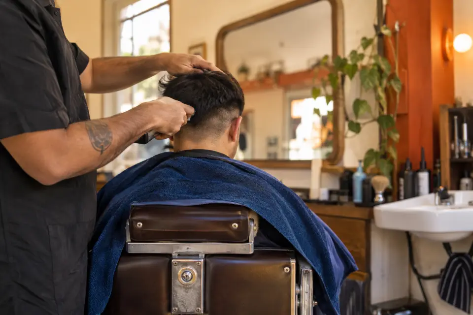 Barbero cortando el pelo a un cliente en una barbería de barrio