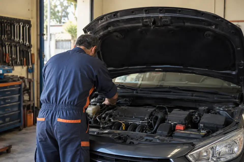 Mecánico revisando el motor de un auto en un taller de barrio